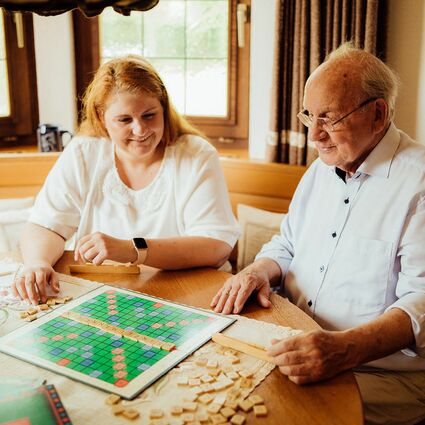 Senior und Seniorenbetreuer spielen mit Brettspiel