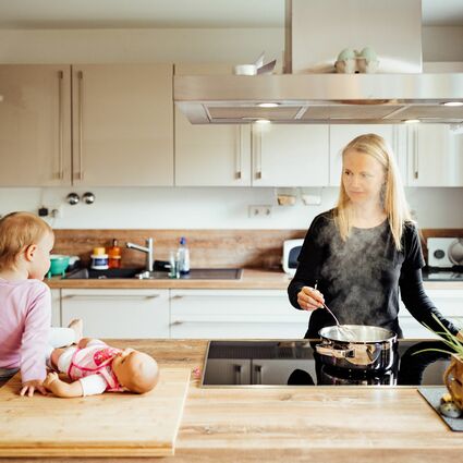 Familienbetreuerin kocht, während ein Kind zu schaut.