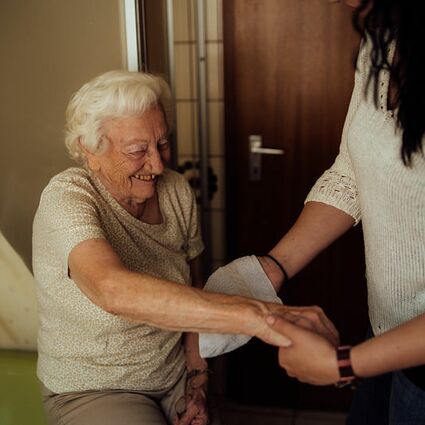 Seniorenbetreuer wäscht Seniorin den Arm