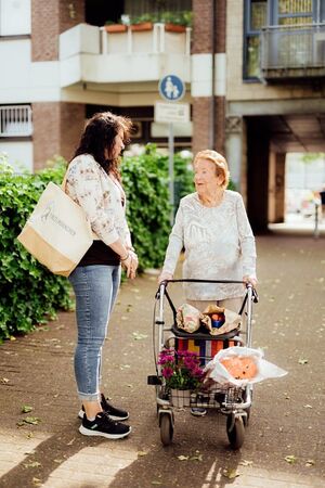 Seniorin und Seniorenbetreuerin gehen in der Stadt spazieren